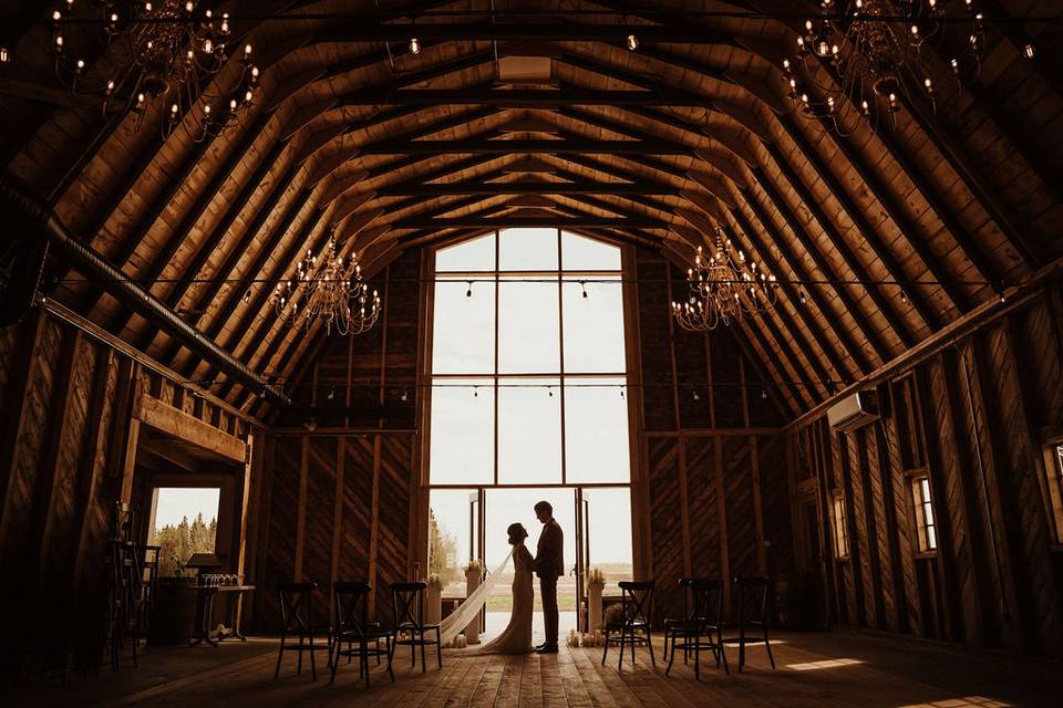 Silhouette of Bride and groom posing in rustic barn location.